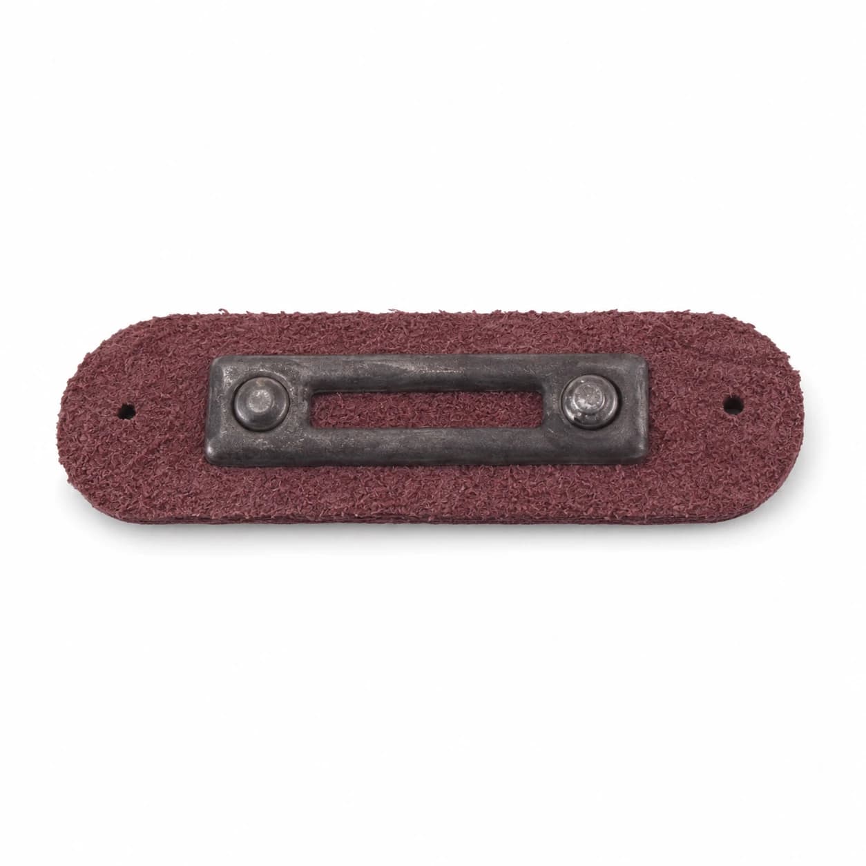 An antique bronze metal tag pressed onto leather — a finished custom hardware piece