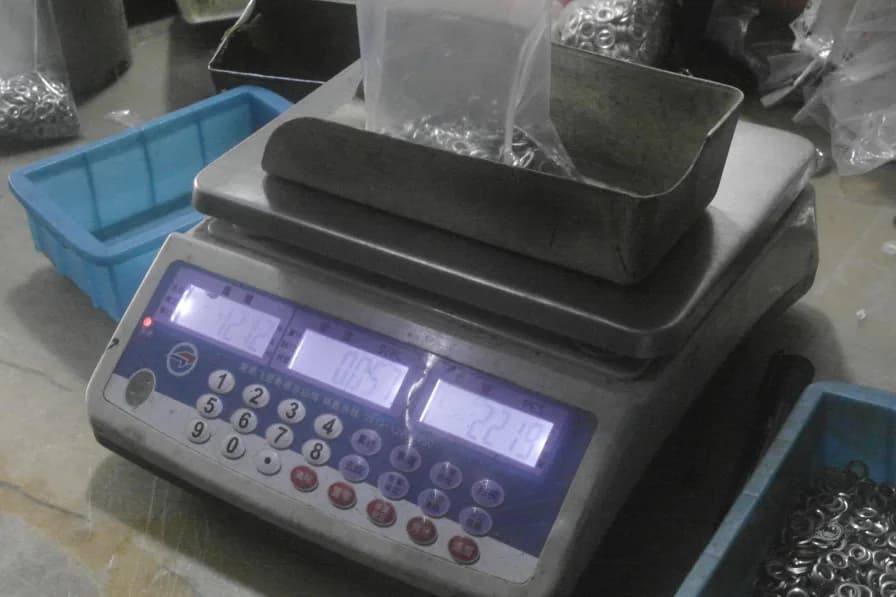 A digital counting scale tallying a batch of finished metal parts during inspection